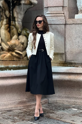 a lady in a black formal dress with a belt and a white  crop jacket